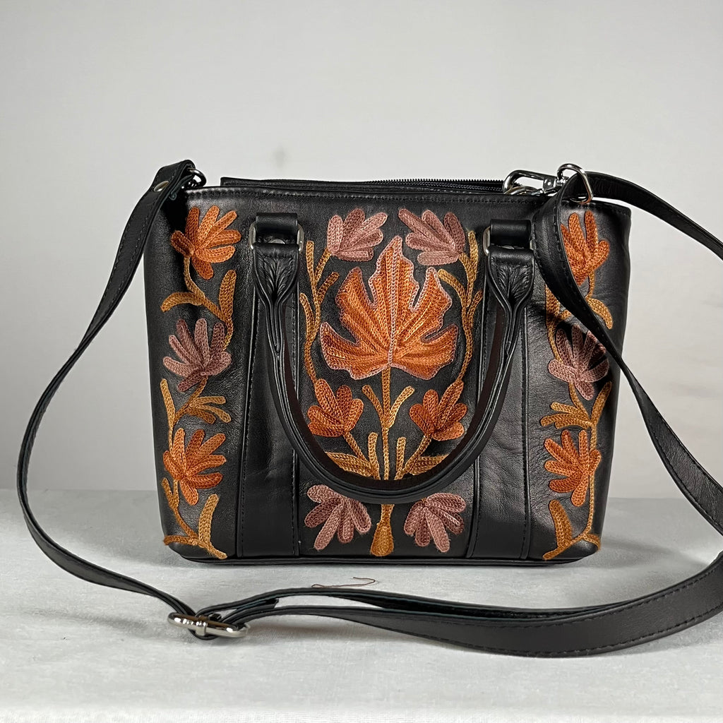 Close-up of Aari embroidery on black leather tote bag