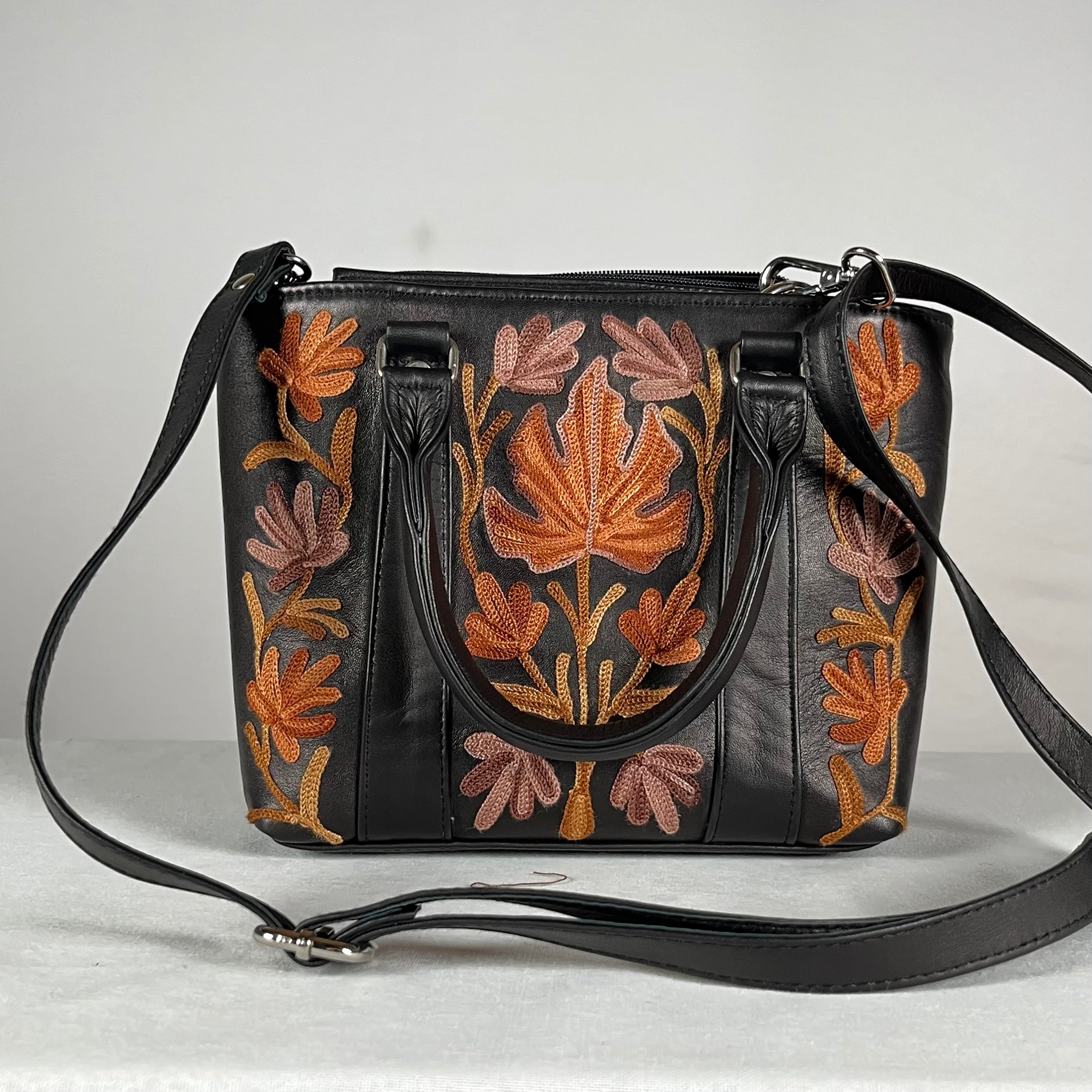 Close-up of Aari embroidery on black leather tote bag