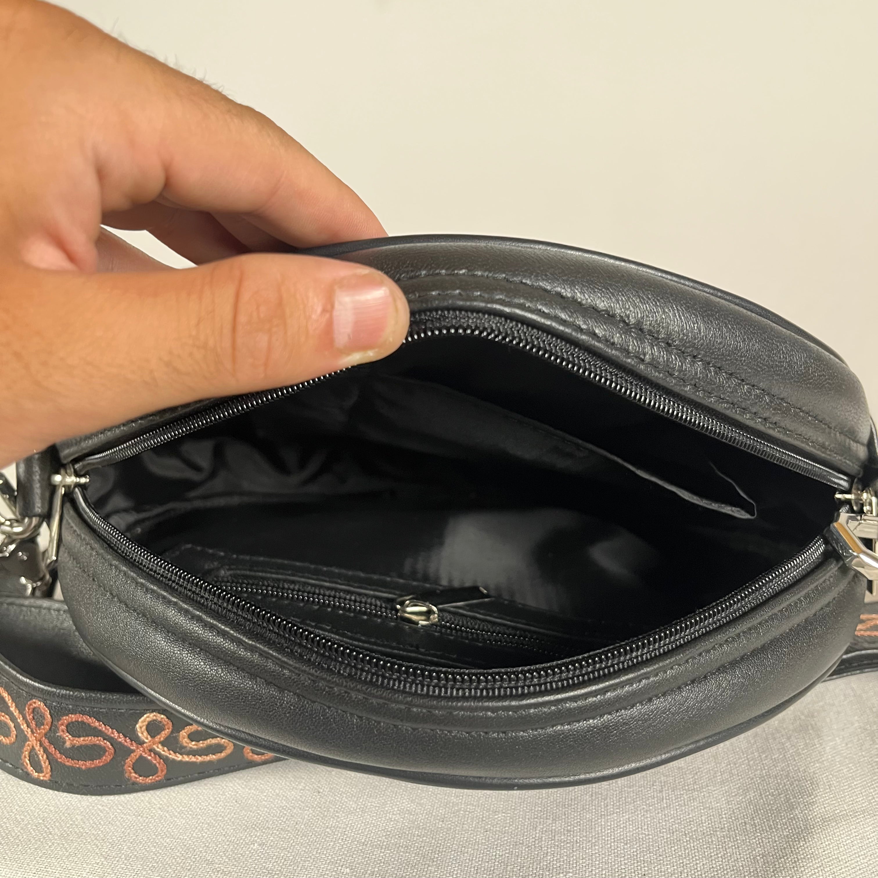 Black leather circle bag shown with detachable embroidered sling
